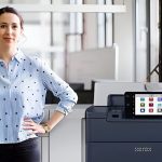 Eine Frau steht neben dem Xerox® PrimeLink® C9200 Serie Drucker in einer modernen Büroumgebung Eine Frau steht neben dem Xerox® PrimeLink® C9200 Serie Drucker in einer modernen Büroumgebung