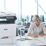 Xerox® VersaLink® C625 Farb-Multifunktionsdruckeram Arbeitsplatz Zwei Frauen arbeiten in einem Büro neben einem Xerox® VersaLink® C625 Farb-Multifunktionsdrucker