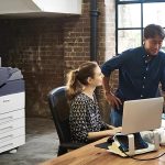 Ein Mann und eine Frau stehen nebeneinander vor einem Computer und konzentrieren sich auf den Bildschirm. Der Xerox® VersaLink® C7000 Farbdrucker ist im Hintergrund zu sehen. Ein Mann und eine Frau stehen nebeneinander vor einem Computer und konzentrieren sich auf den Bildschirm. Der Xerox® VersaLink® C7000 Farbdrucker ist im Hintergrund zu sehen.